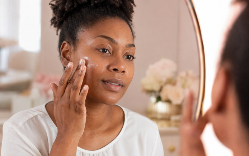 Adult Black woman applying moisturizer before makeup at a blush-and-cream vanity